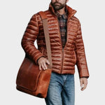 Man wearing a brown quilted jacket holding a brown leather bag on a white background